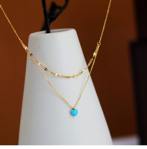 Close-up of golden double-layered necklace with a blue heart-shaped faux opal pendant