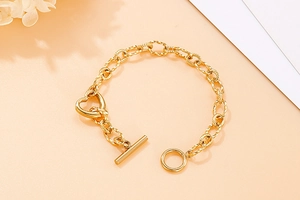 Detail of gold-plated chain bracelet featuring heart charms and toggle OT clasp closure