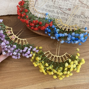 Macro detail of elegant U-shaped flower hairpins in four colors on a classical wood surface
