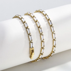 Close-up of three rows of gold-plated tennis bracelets with rectangular clear zircons