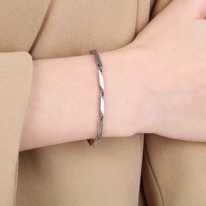 Close-up of a silver geometric diamond-cut link bracelet on a khaki suit sleeve