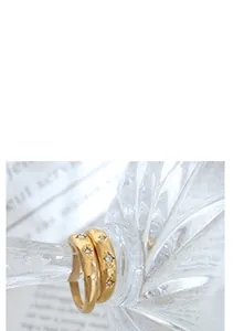Detail von 18k vergoldeten Halsketten am Glasrand mit Vintage-Magazin im Hintergrund