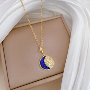 Macro detail of gold star and moon pendant with blue center on a beige jewelry box