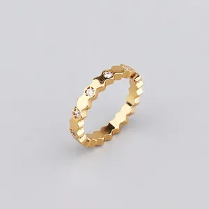 Close-up of golden geometric hexagonal ring with round white zircon stone inlays