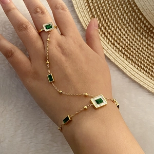 Detailed shot of emerald heart finger bracelet on a white plush background