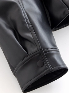 Close-up of black PU leather sleeve cuff with metal snap button and reinforced stitching