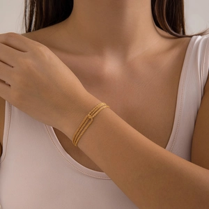 Close-up of triple layered gold chain bracelet worn on wrist for minimalist style