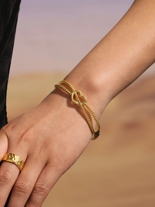 Détails d'un bracelet doré avec cœur et d'une bague large texturée sur un mannequin