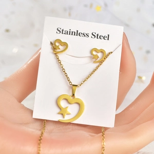 Detail of gold stainless steel necklace and stud earrings set with heart and star patterns