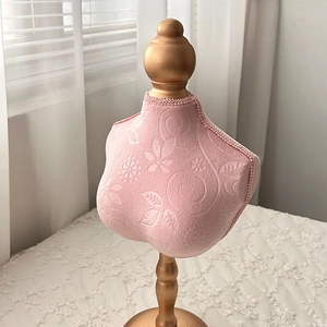 Close-up of pink velvet jewelry mannequin stand with golden base and floral texture
