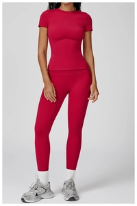 Full body shot of a woman in red high-waisted yoga pants and matching tight short sleeve top