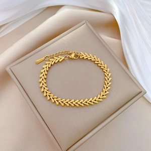 Elegant gold titanium V-shaped chain bracelet on silk background with lobster clasp