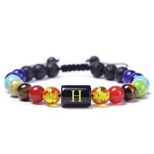 Detailed shot of adjustable beaded bracelet with colorful natural stones and letter H charm