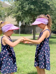 Kids outdoor sun visor hat in purple and pink shown on children in a sunny park