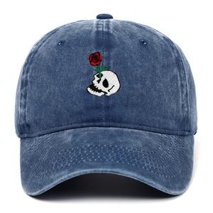 Detailed close-up of skull and rose embroidery on navy blue washed denim baseball cap