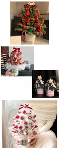 Close-up of a mini Christmas strawberry tower flower box with festive ribbons and pine