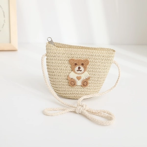 Close-up of children's straw crossbody bag with cute brown teddy bear embroidery detail