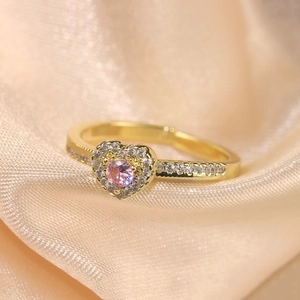 Macro side view of pink heart stone ring with cubic zirconia on champagne silk