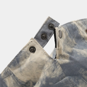 Macro view of blue tie-dye fabric texture and high-quality dark grey metal snap button