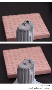 Detail of punk style hexagram stud earrings with black and rose red gemstones