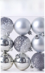 Detail of 9 silver Christmas baubles in matte, glossy, and glitter finishes in a clear box