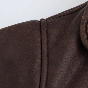 Macro view of shoulder stitching details on a vintage brown leather jacket coat