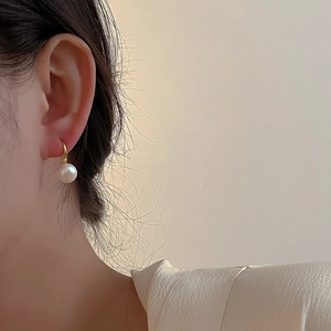 Elegant minimalist natural freshwater pearl earrings with gold hooks worn by a model