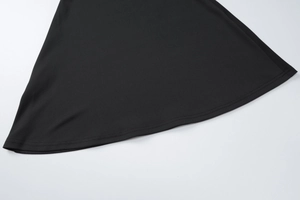Gros plan détaillé sur la texture du tissu noir et les coutures de l'ourlet de la robe