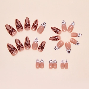 Gros plan d'ongles stiletto à coller avec nœuds rouges et motifs floraux dentelle