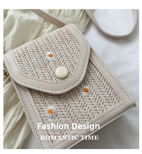 Detailed view of woven phone bag with daisy embroidery and beige leather trim