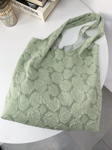 Close-up of light green tote bag featuring intricate rose floral embossed fabric texture