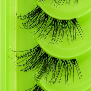 Macro shot of dense curly black synthetic false eyelashes in a green plastic tray