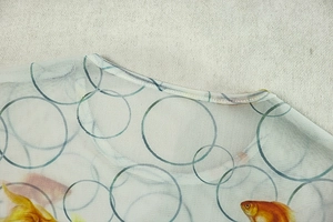 Detail of round neckline and sheer mesh fabric with goldfish and geometric print