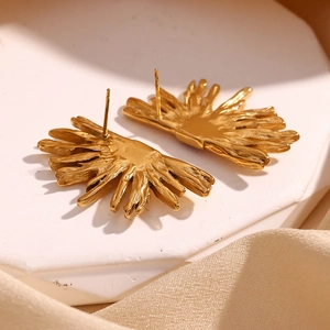 Macro shot of 18K gold plated starfish earrings on white stone with silk background