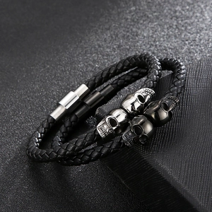 Detail of woven leather bracelets with silver and black skull beads and magnetic clasps