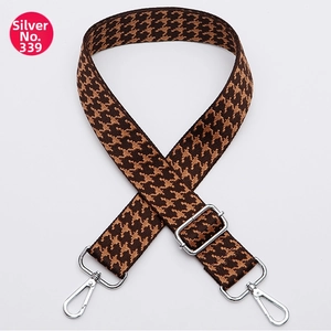 Close-up of houndstooth patterned bag strap with silver metal hooks on white background
