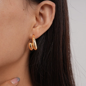 Close-up detail of a thick chunky gold C-shaped earring worn on a model's ear