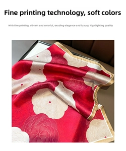 Close-up of silk scarf featuring elegant red and gold floral patterns on dark leather