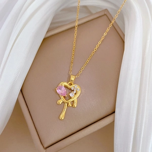Macro shot of a gold melting heart pendant with pink gemstone and diamonds in a jewelry box