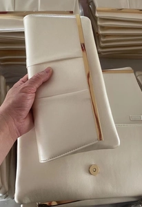 Detail of white pearlescent leather evening clutch with gold metal trim and magnetic snap