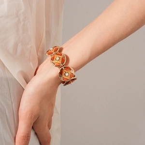 Detailed shot of vintage gold chain bracelet with orange enamel and pearls on model's wrist
