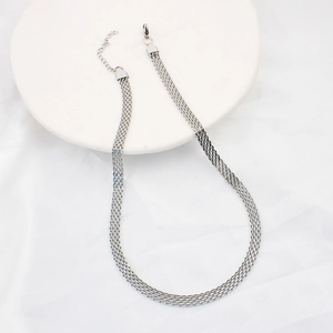 Detail of silver multi-strand mesh chain necklace on white tray with silk backdrop