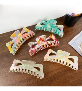 Detailed view of oversized hollow acetate hair claws in various marble patterns on a desk