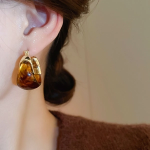Macro detail of amber resin U-shaped earrings with vintage gold-tone metal base