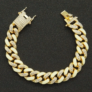 Detailed close-up of golden Cuban link bracelet with sparkling rhinestones and white enamel