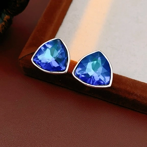 Gros plan sur des boucles d'oreilles triangulaires avec cristaux bleus et bords argentés
