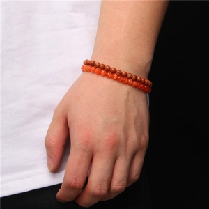 Detail of double-layer 6mm carnelian and goldstone beaded bracelets on a wrist