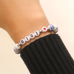 Dettaglio del bracciale con perline GIGI e ceramica a fiori blu indossato al polso