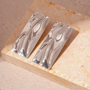 Macro view of silver rectangular earrings with liquid metal rippled texture on stone