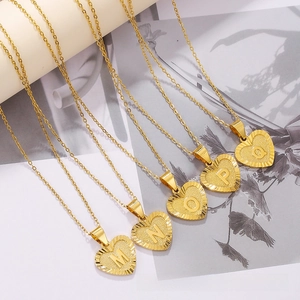 Detailed view of gold heart initial necklaces with engraved radial patterns M to Q